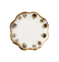 The Amoria Dinnerware by Blue Pheasant features a round ceramic plate with a wavy, scalloped edge, showcasing a white center complemented by a brown and gray reactive glaze pattern along the rim for vintage-inspired elegance.