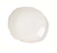 A round, off-white ceramic plate from the Plume White Dinnerware Pearl collection by Jars - Rosenthal, featuring a subtle textured pattern and a gently wavy edge, photographed on a white background.