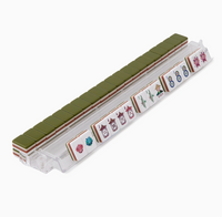 A clear rack holds Oh My Mahjong’s Mahjong Tiles Set - Drake, featuring luxury acrylic tiles. Most tiles display sleek green backs, while some faces showcase traditional Mahjong symbols like flowers, bamboo, circles, and Chinese characters for a sophisticated touch.