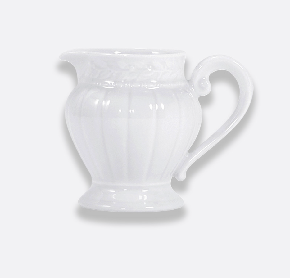 The Louvre Dinnerware ceramic pitcher by Bernardaud features a decorative handle and embossed pattern inspired by Renaissance French architecture, displayed against a plain light gray background.