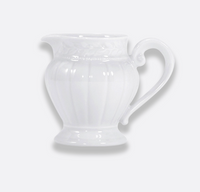 The Louvre Dinnerware ceramic pitcher by Bernardaud features a decorative handle and embossed pattern inspired by Renaissance French architecture, displayed against a plain light gray background.