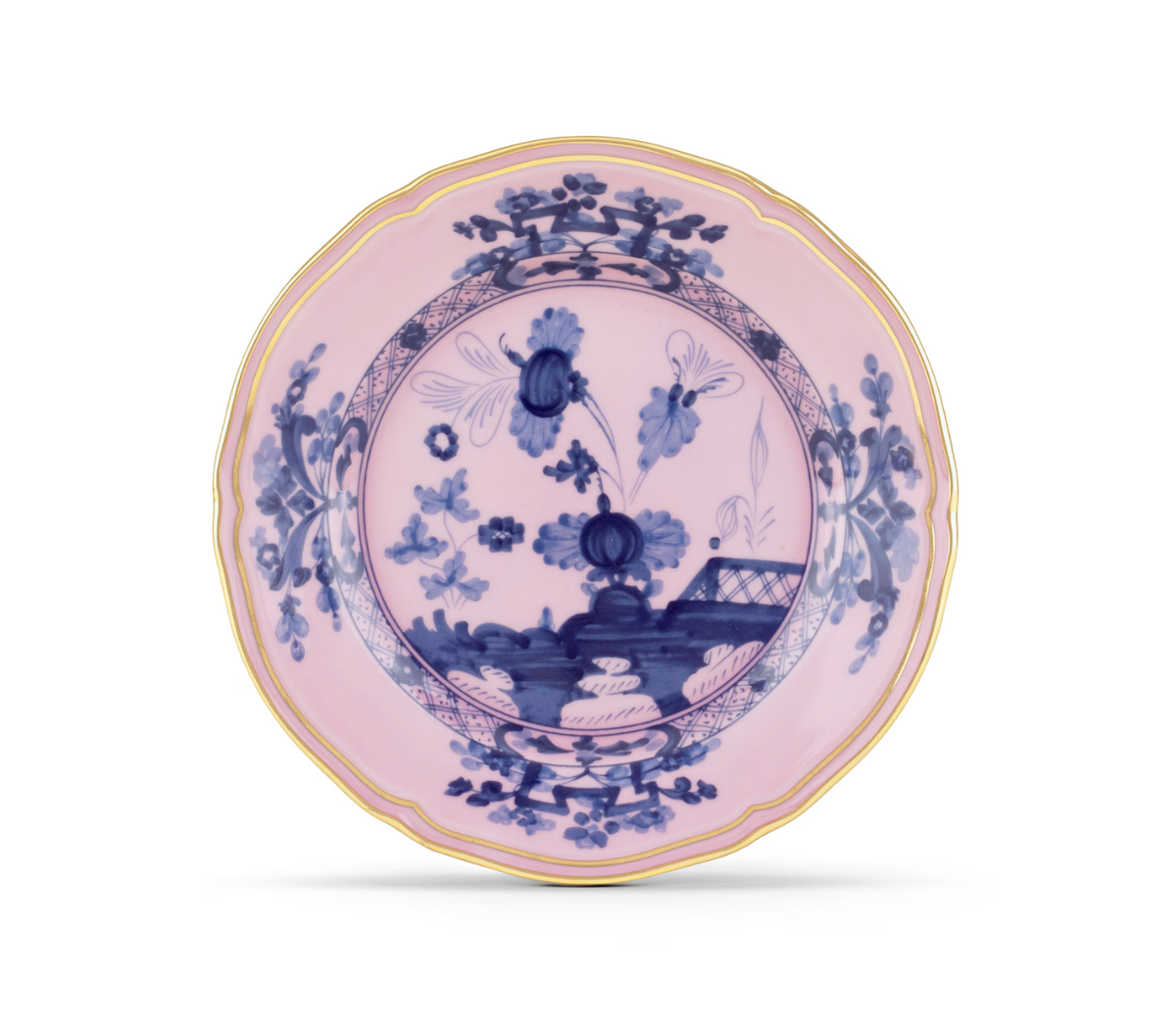 An Oriente Italiano Dinnerware Azalea porcelain plate by Ginori 1735, showcasing a pink background with blue chinoiserie-inspired floral and garden motifs, and finished with a delicate gold rim, viewed from above against a white background.