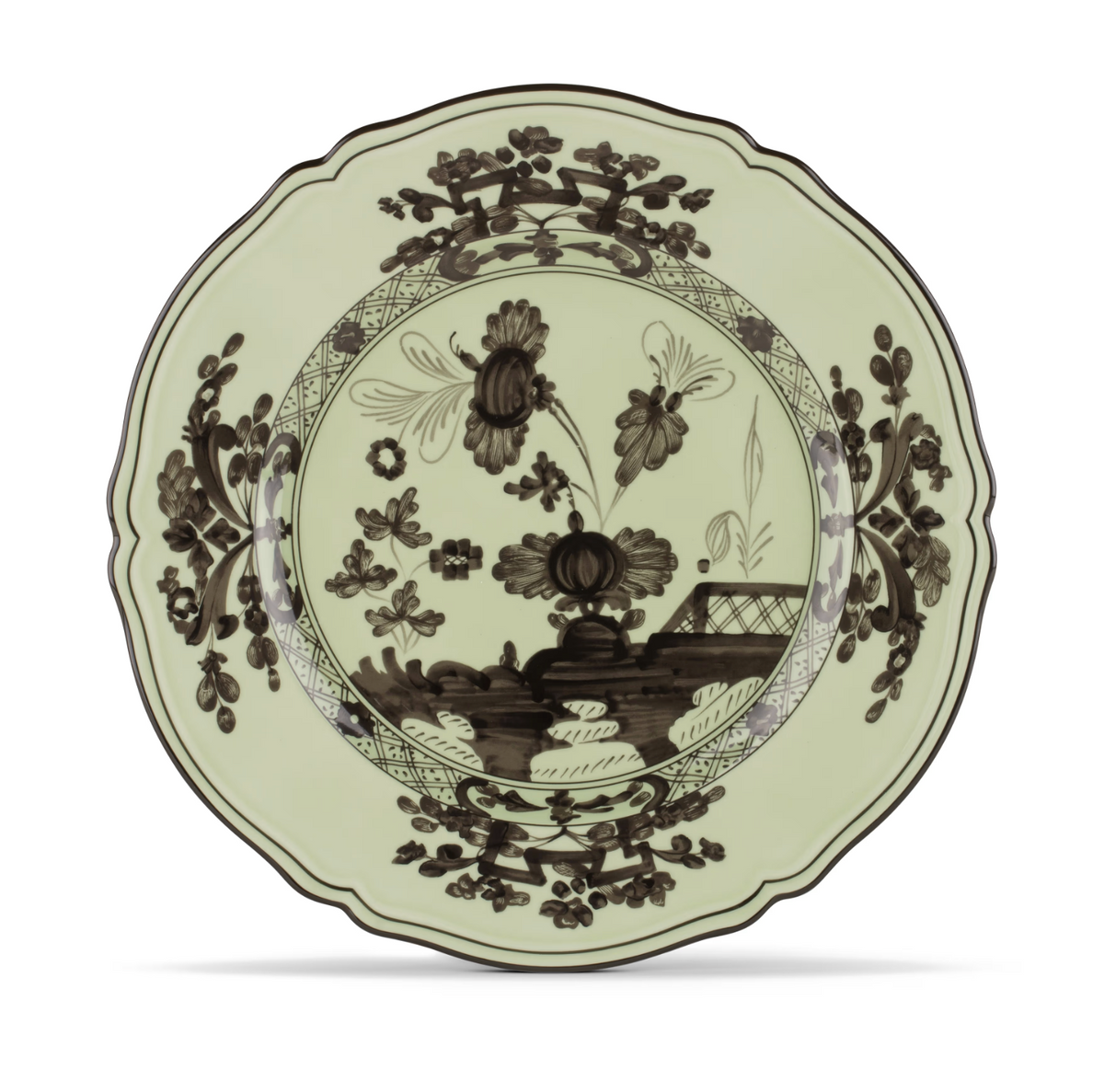 A decorative ceramic plate from Ginori 1735, the Oriente Italiano Dinnerware Bario, with scalloped edges and a black floral and nature-inspired motif on a pale green background, inspired by chinoiserie style.