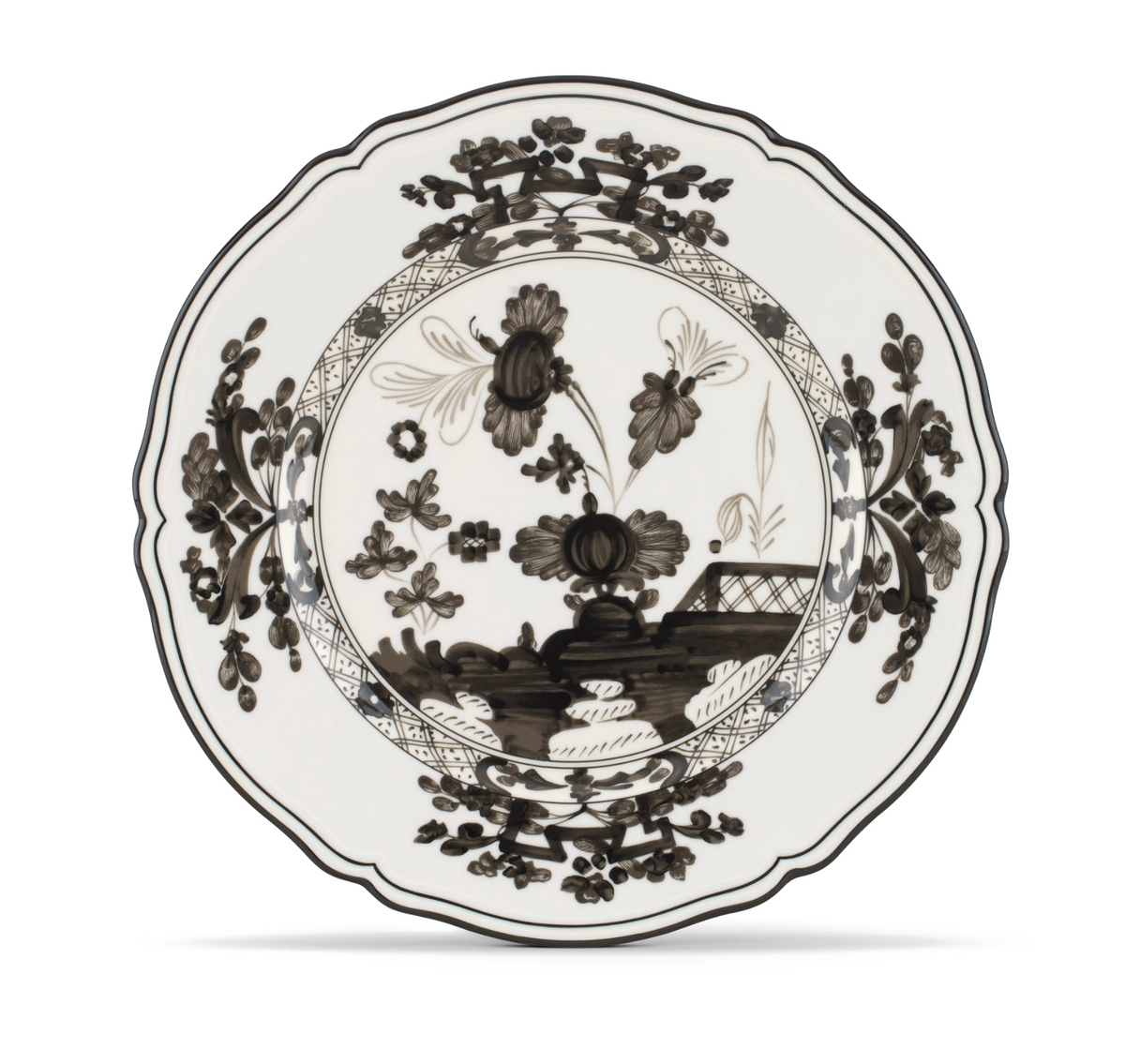 Oriente Italiano Dinnerware Albus by Ginori 1735 is a white plate adorned with an intricate black floral design featuring large flowers, leafy motifs, and a decorative border. Reminiscent of classic chinoiserie dinnerware, this plate showcases a scalloped edge and elaborate patterns throughout.