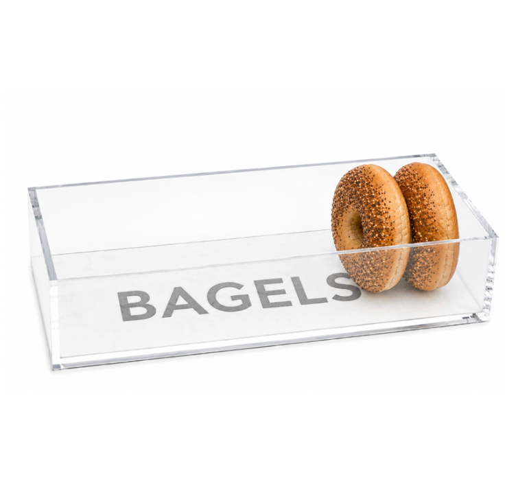 A clear, rectangular Eye Candy Bagel Tray labeled “BAGELS” holds two sesame bagels inside and is positioned near the right side of the food-safe container—making it a thoughtful gift for any breakfast lover.