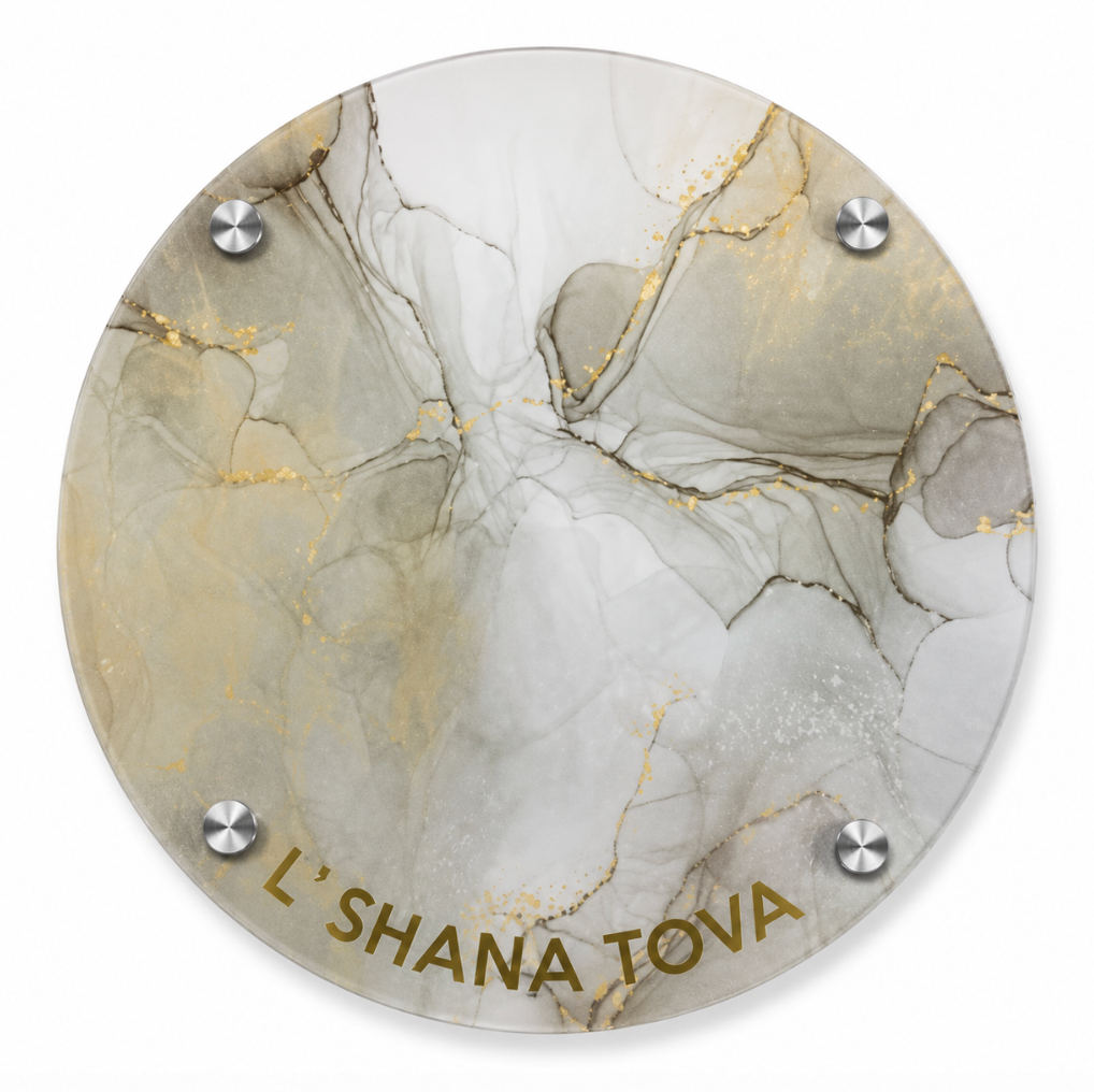 The Eye Candy Round Challah Board in beige, brown, and gold features a marbled design with gold accents, is secured by four metal screws, rests on elegant silver feet, and displays “LSHANA TOVA” in gold at the bottom—making it a stunning choice for your holiday table.