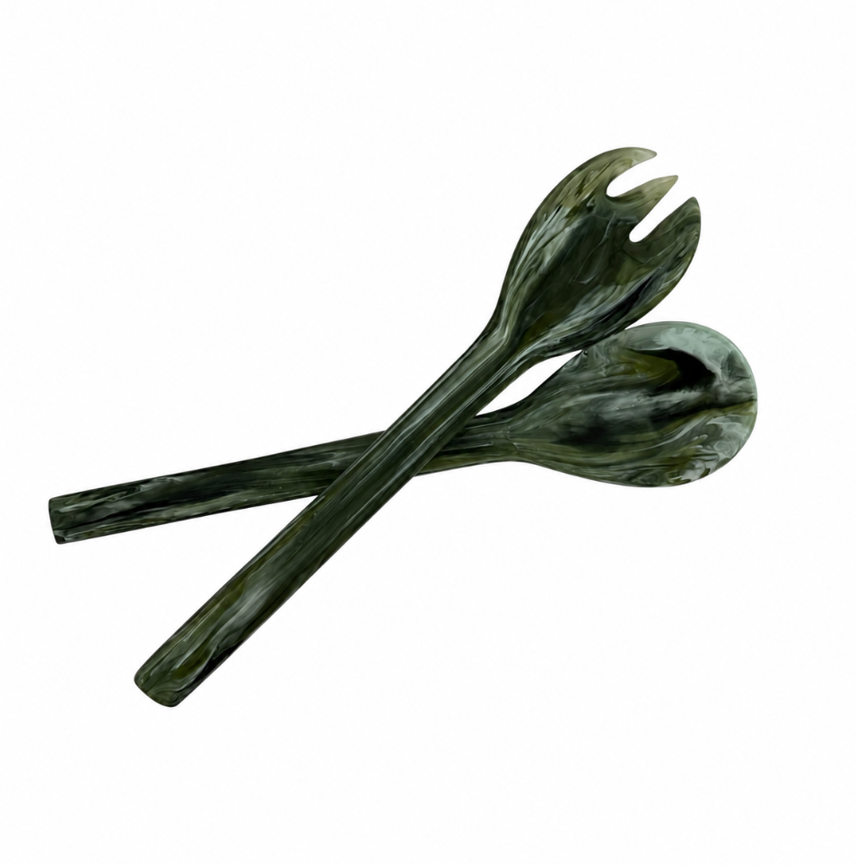 Two Swirl Colored Resin Everyday Salad Servers in Forest by Nashi Home—one spoon and one fork—are crossed on a white background, highlighting the elegant handcrafted design of this stylish, BPA-free serveware.