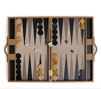 The Gene Leather Backgammon - Taupe by Zodax is shown open, with tan and black playing pieces arranged on the board’s triangles, two dice displaying three and five pips, and brown handles on either side.