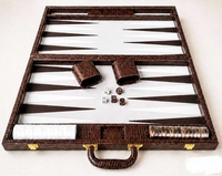 An open Nile Backgammon Brown 21″ by Tizo displays two dice cups, white and brown checkers, and four dice neatly arranged on its brown playing surface.