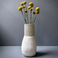 Cream-colored Chain Bottle Vase Cream 11″ by CYM Warkov Ceramics, an unglazed porcelain vase with a textured chain-link pattern neck, holding a bouquet of yellow billy button flowers.