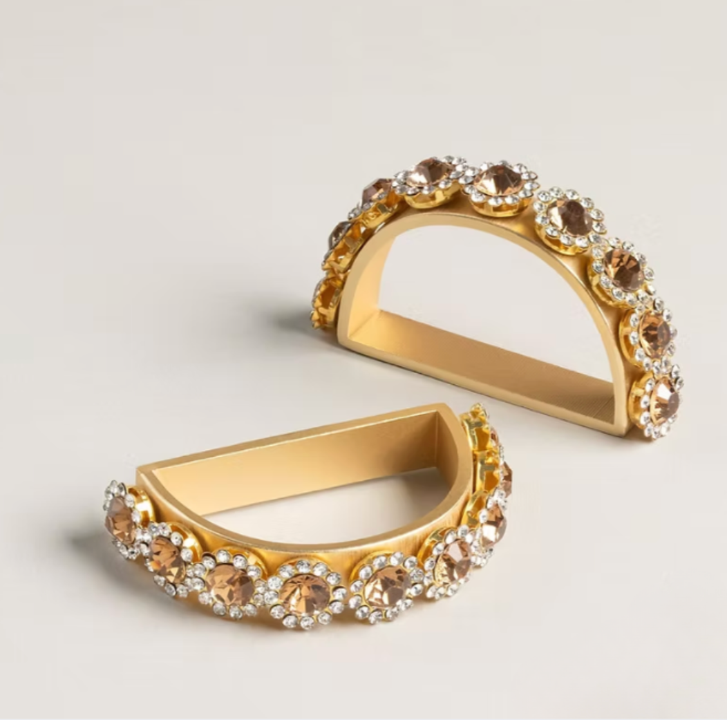 A set of four semicircular Golden Bar Napkin Ring napkin rings decorated with rows of amber-colored and clear rhinestones, serving as elegant handcrafted table jewelry.