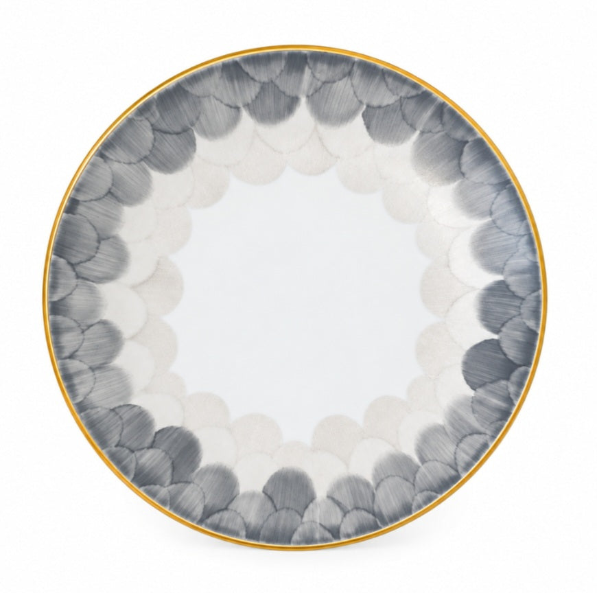 Marie Daâge Cercle D’Ecailles Platinum Filet round Limoges porcelain plate with a gold rim and a border of overlapping grey and white scalloped patterns.