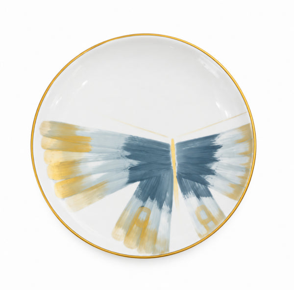 Marie Daâge Belle De Nuit 1 white Limoges porcelain plate featuring a gold rim and a hand-painted blue and gold butterfly wing motif.