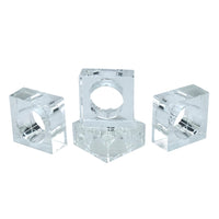 Four Crystal Cube Napkin Rings by Tizo are arranged together, highlighting a stylish set of four perfect for any table setting. Each clear napkin ring features a square block design with a circular center to hold your napkins. The display is set against a white background.