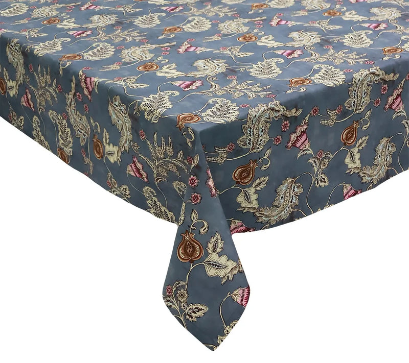 A rectangular table covered with the Kim Seybert Paisley Vine Tablecloth in Blue & Gray (54x126″)—a blue and gray tablecloth featuring an intricate floral and paisley pattern in cream, brown, and pink accents.