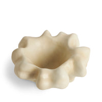 A small, irregularly shaped, cream-colored L’Objet Timna Coupe - Latte porcelain bowl with a wavy, organic rim evokes the allure of King Solomon’s Mines, set against a white background.