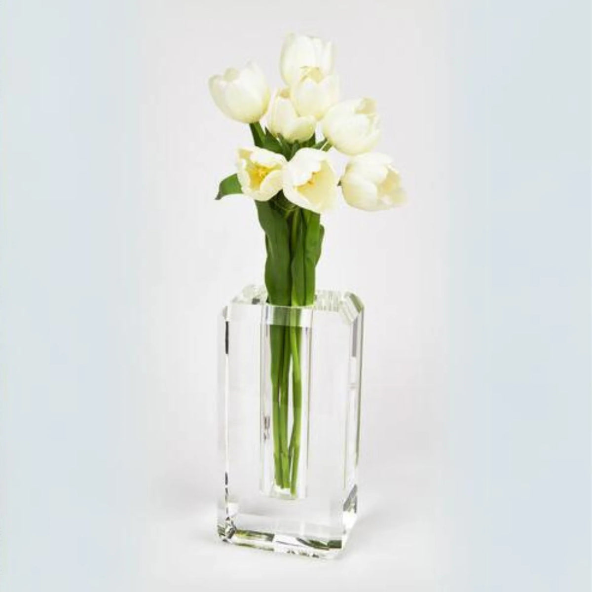 A bouquet of white tulips with green stems arranged in the Hex Edge Vase Large by Tizo, set against a plain, light background.