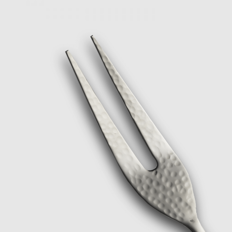A close-up of the Versa Meat Serving Fork by Mary Jurek, featuring two prongs and a hammered metallic design, displayed against a plain light gray background.