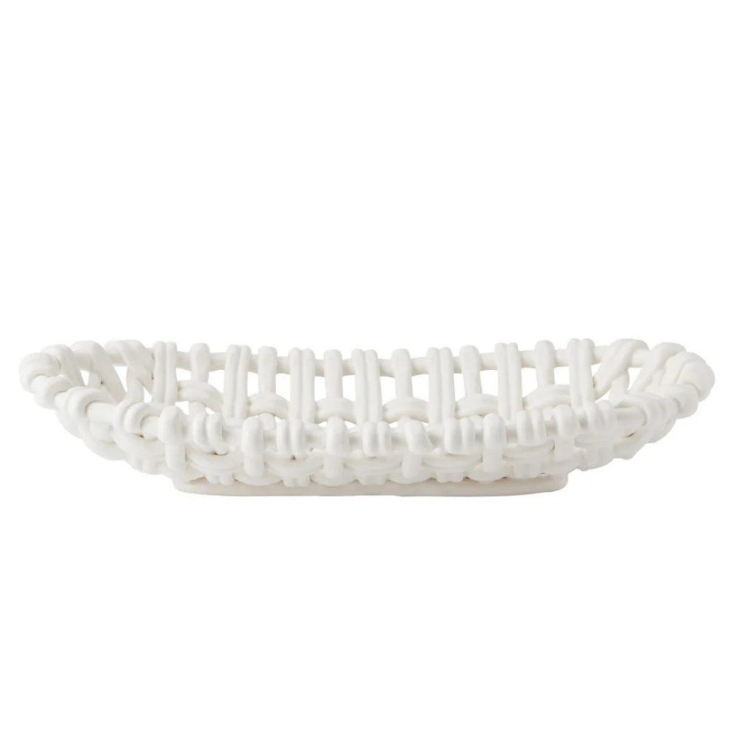 The Skyros Woven Basket Oval is a white, handwoven basket with a lattice design, crafted by artisans in Condeixa, Portugal. It has an oval shape and is pictured from the side against a plain white background.