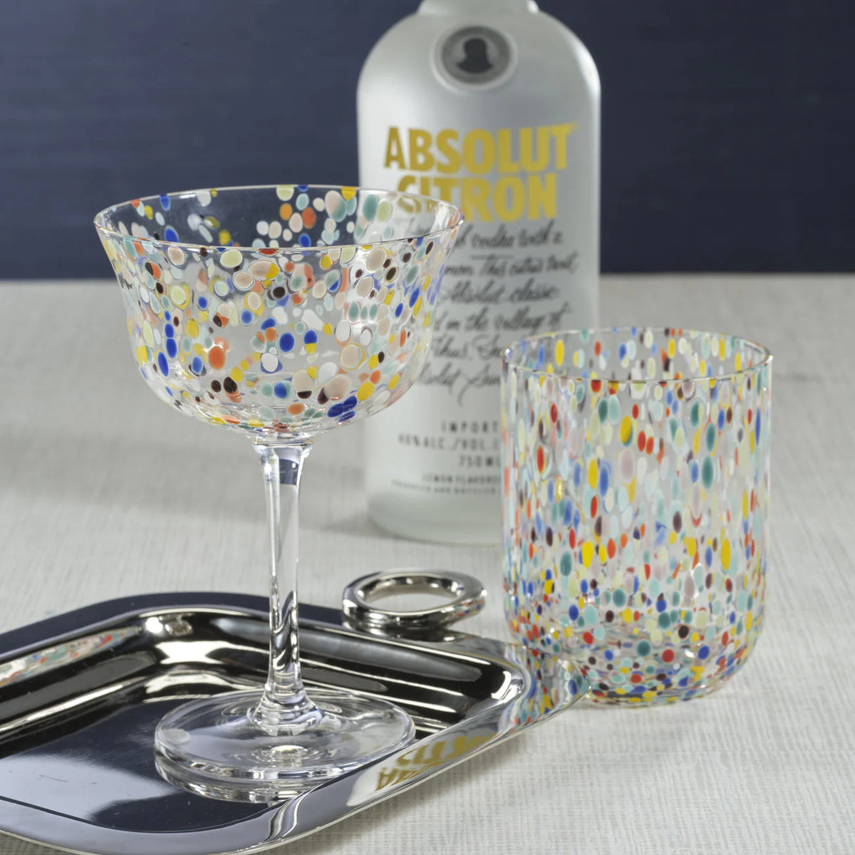 A Spritz Sprinkles Tumbler by Zodax sits on a silver tray beside a bottle of Absolut Citron, creating a playful and festive tableware display.