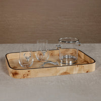 The Zodax Valari Rectangle Serving Tray in light burl veneer holds two stemless glasses with silver deer accents, a clear ice bucket with a silver lid, and a deer antler-shaped silver bottle opener on a beige surface.