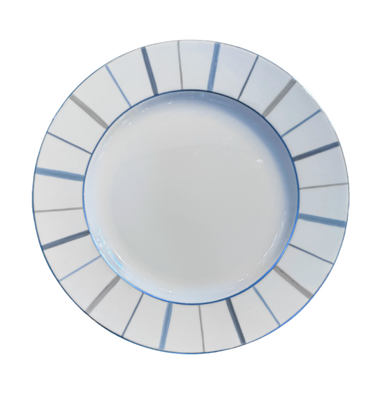 A round white ceramic plate by Marie Daâge, the Berlingot Platinum Trim, features blue and gray lines radiating on its wide rim. Photographed from above, the empty plate evokes the elegance of hand-painted Marie Daâge tableware.