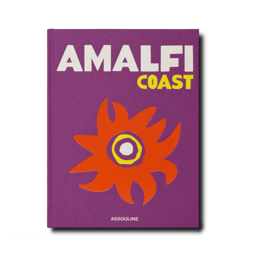 Amalfi Coast Book by Assouline features bold white and yellow lettering on a purple cover with an abstract orange and yellow sun design, perfect for anyone inspired by the stunning Amalfi Coast.