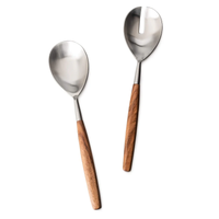 The Barre 2pc Serving Set by Simon Pearce, featuring two metal utensils with wooden handles—one solid spoon and one slotted spoon—are placed side by side on a white background.
