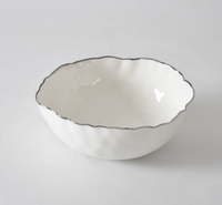 The PAMPA BAY Portofino Plata Bowl is a white porcelain medium bowl featuring a wavy rim and elegant silver trim, displayed on a plain white surface.