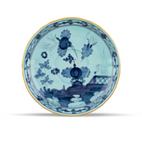 Light blue Ginori 1735 Oriente Italiano Dinnerware Iris porcelain saucer featuring a gold rim and a dark blue hand-painted chinoiserie floral and landscape pattern.