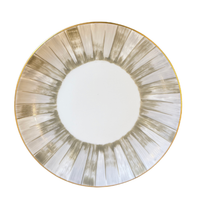 The Marie Daage Panache round white plate by Marie Daâge is crafted from luxury Limoges porcelain and showcases a hand-painted sunburst pattern in metallic gold and silver radiating from the center, finished with a delicate gold rim—an exquisite example of artisan tableware.