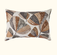 The Moonflower Pillow 16 x 24 by Threads Soft Goods features a white linen background with an embroidered abstract leaf pattern in brown, tan, and gray.