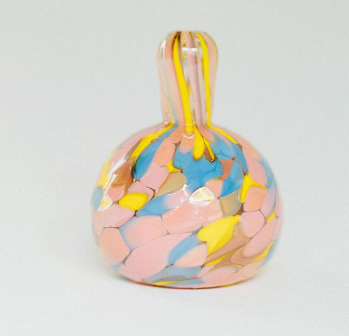 From the Jelly Baby Mini Vase Collection by Maria Ida Designs, this round glass mini vase with a short neck showcases a mosaic pattern in pastel pink, blue, yellow, and white on a light background—embodying the charm of handmade art glass for truly unique home decor.