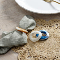 Decorative rings on a textured placemat with a white plate in the background