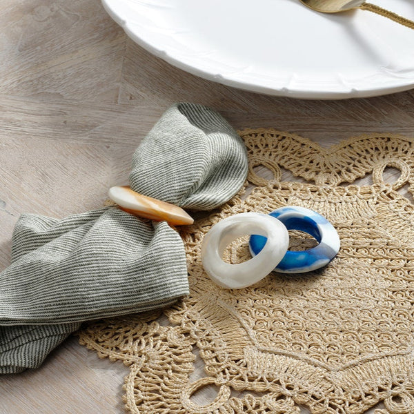 Decorative rings on a textured placemat with a white plate in the background