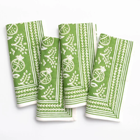 The Pomegranate Napkin Set of 4 by Pomegranate features green cotton napkins with white botanical and fruit patterns, including pomegranates, neatly folded and arranged side by side on a white background.