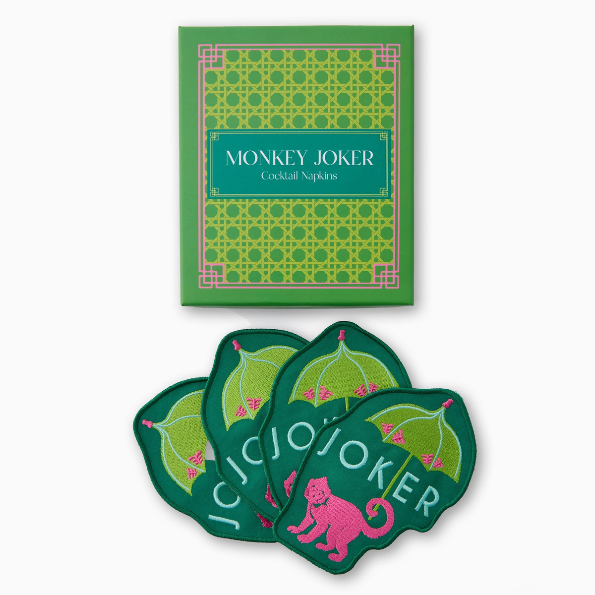 The Oh My Mahjong Money Joker Cocktail Napkin Set includes green napkins shaped like leaves, adorned with pink monkeys and “JOKER” in pink. The set comes in a green box with a geometric pattern and “Money Joker Cocktail Napkin Set” on the front.