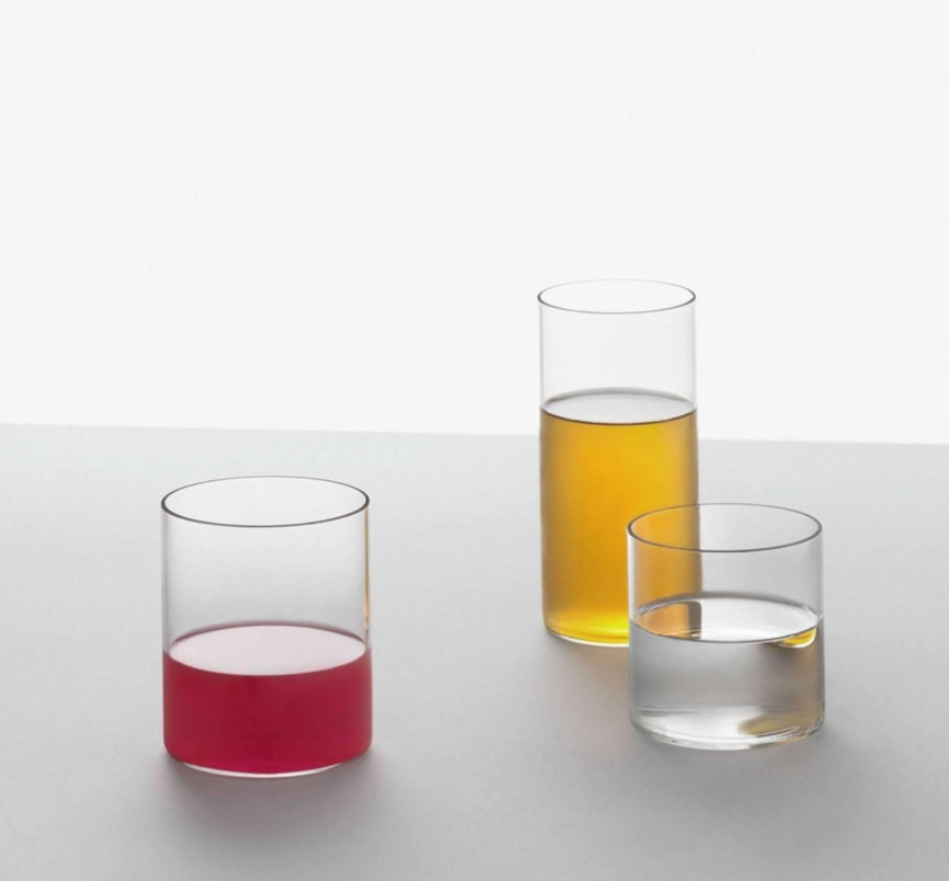 Three Ichendorf Milano Cilindro Extra Light Drinkware glass cylinders filled with red, yellow, and clear liquids on a white surface.