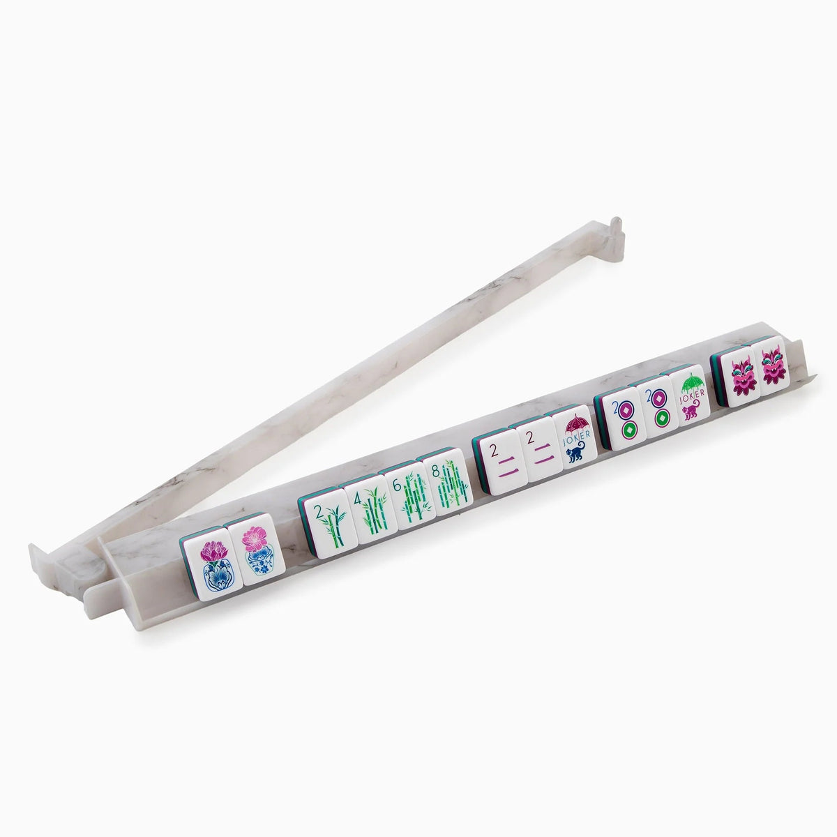 A set of ten Mahjong tiles with vibrant motifs—flowers, bamboo, circles, and Chinese characters—displayed on the Oh My Mahjong Carrara Marble Rack & Pusher Set, with an additional Carrara piece positioned behind.