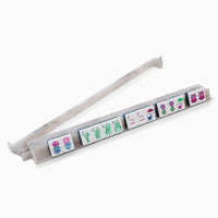 A set of ten Mahjong tiles with vibrant motifs—flowers, bamboo, circles, and Chinese characters—displayed on the Oh My Mahjong Carrara Marble Rack & Pusher Set, with an additional Carrara piece positioned behind.