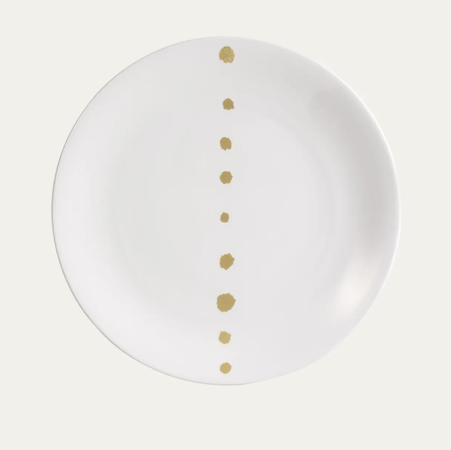 The Dibbern Golden Pearls Dinnerware Dessert Plate is crafted from white bone china and features a straight line of golden pearls down the center, graduating in size from top to bottom.