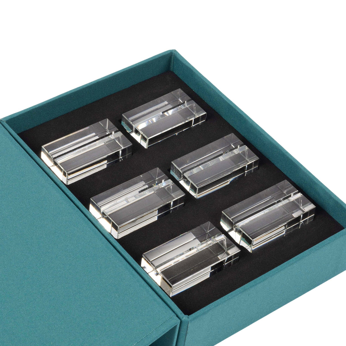 Six Clara Place Card Holders by Dear Annabelle, in clear crystal, are arranged in two rows inside a teal box with a black foam insert. The partially open lid reveals the elegant set of six—perfect for a modern tablescape.