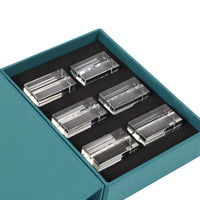 Six Clara Place Card Holders by Dear Annabelle, in clear crystal, are arranged in two rows inside a teal box with a black foam insert. The partially open lid reveals the elegant set of six—perfect for a modern tablescape.