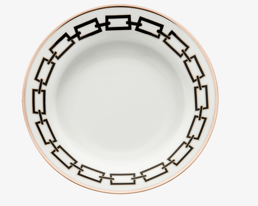 The Ginori 1735 Catene Nero Dinnerware features a white ceramic plate adorned with a black geometric chain-link pattern around the rim and finished with a thin gold edge.
