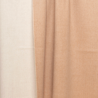 Two panels of fabric drape gracefully side by side; the left panel is a soft beige and the right an inviting ivory, both exuding a gentle sheen. Their silky-smooth texture and subtle vertical folds are evocative of the Reversible Alpaca Throw - Beige & Ivory from Thread & Butter, capturing the understated luxury and refined warmth characteristic of an elegant alpaca throw.