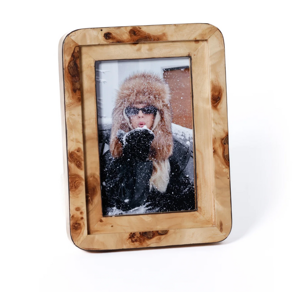 A woman in a fur hat and sunglasses blows snow in a photo displayed in the Zodax Valari Burl Veneer Frame.