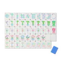A set of Oh My Mahjong’s Mahjong Tiles Set – Moonlight is elegantly arranged in rows, featuring shimmering acrylic tiles with intricate designs such as circles, bamboo, flowers, and labeled NEWS; the set is complemented by a single blue tile displayed beside it.