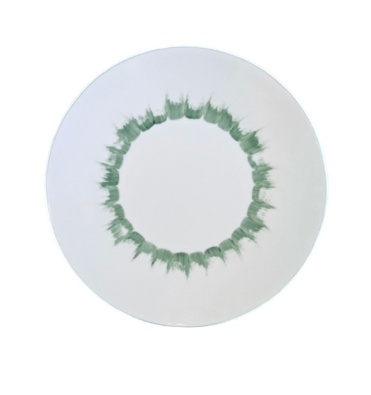 Introducing the Marie Daâge Iris 1 Platinum Rim Dinnerware: a white plate adorned with a circular green brushstroke pattern near the edge, forming a striking ring around the center. Expertly hand-painted on Limoges porcelain by Marie Daâge, this luxury tableware piece exemplifies the timeless elegance and refined presentation of French porcelain craftsmanship. A plain white background and platinum rim add an extra touch of sophistication to its design.