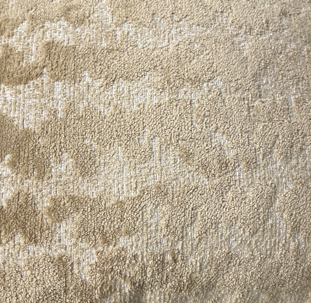 Close-up of the Decor Fifty-Five Coolney Pillow Sand, featuring a beige textured surface with small loops and raised areas for a soft, subtly uneven look.