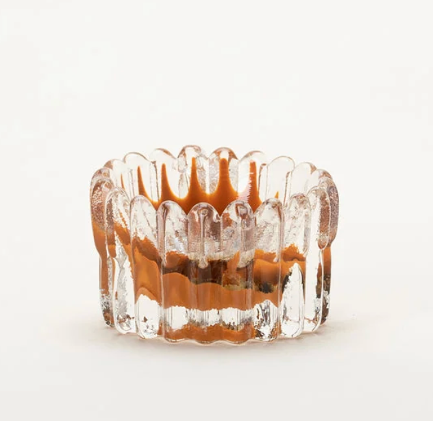 The Splash Catchall Bowl by Gary Bodker, crafted from clear glass with vertical ridges and a wavy rim, features distinctive brownish-orange accents on the inside. Set against a plain white background, its artisanal design and meticulous detailing evoke the charm of a handcrafted decorative dish.